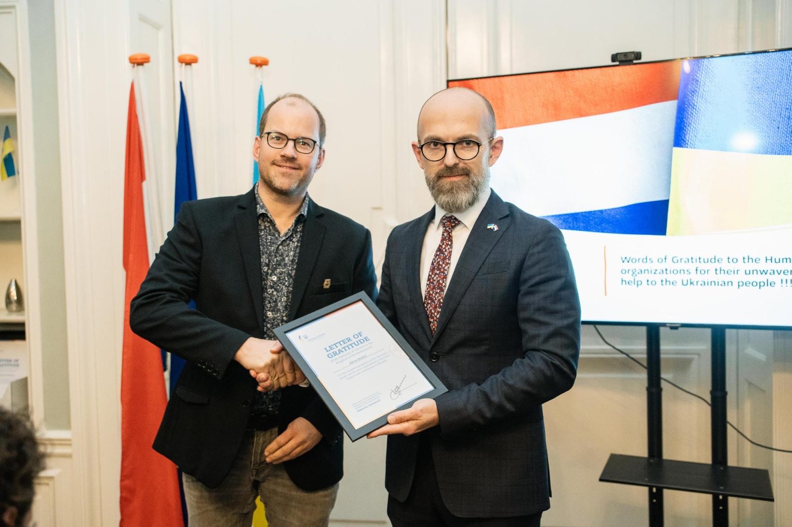 Ambassadeur Oleksandr Karasevych overhandigt een Letter of Gratitude aan bestuurslid Niels.